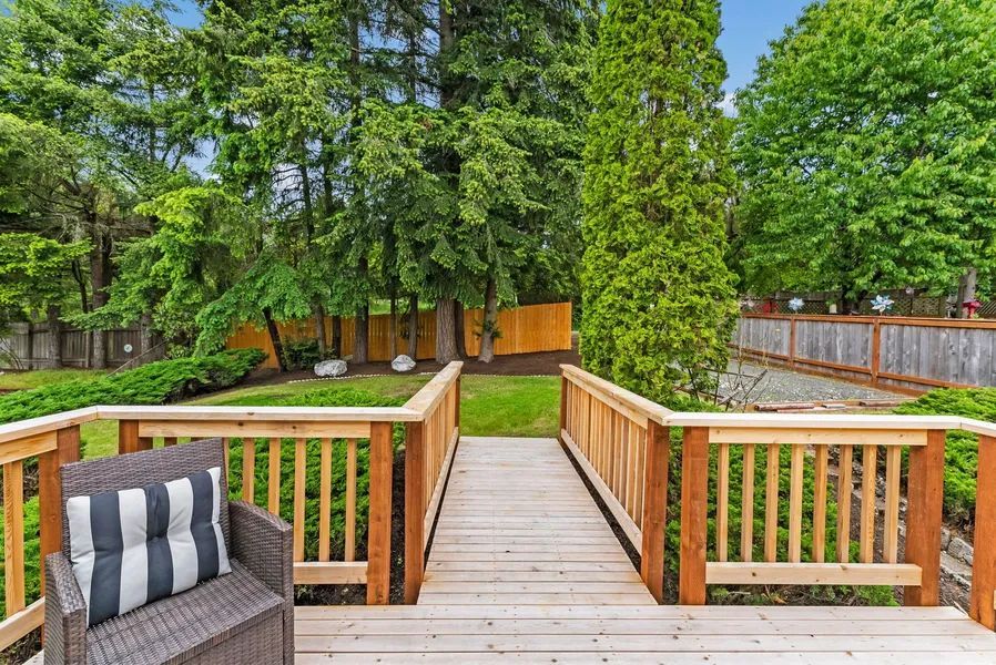 A wooden deck with a chair and a striped pillow on it.
