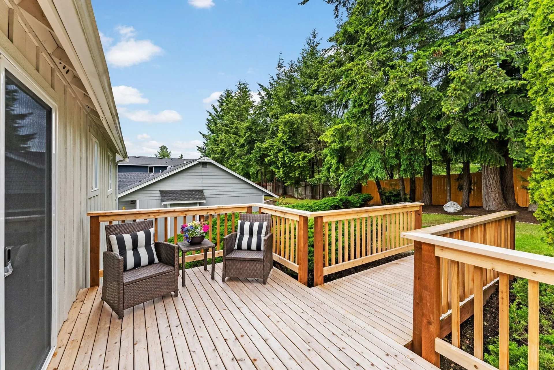 There is a large wooden deck with chairs and a table.