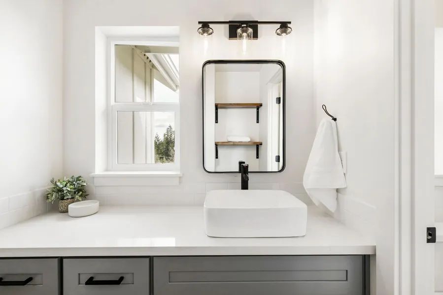 A bathroom with a sink , mirror and window.
