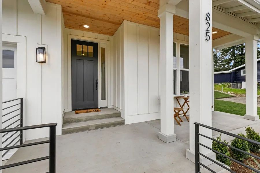 A white house with a black door and a porch.