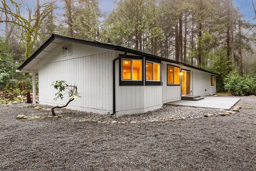 A white house is sitting in the middle of a forest.