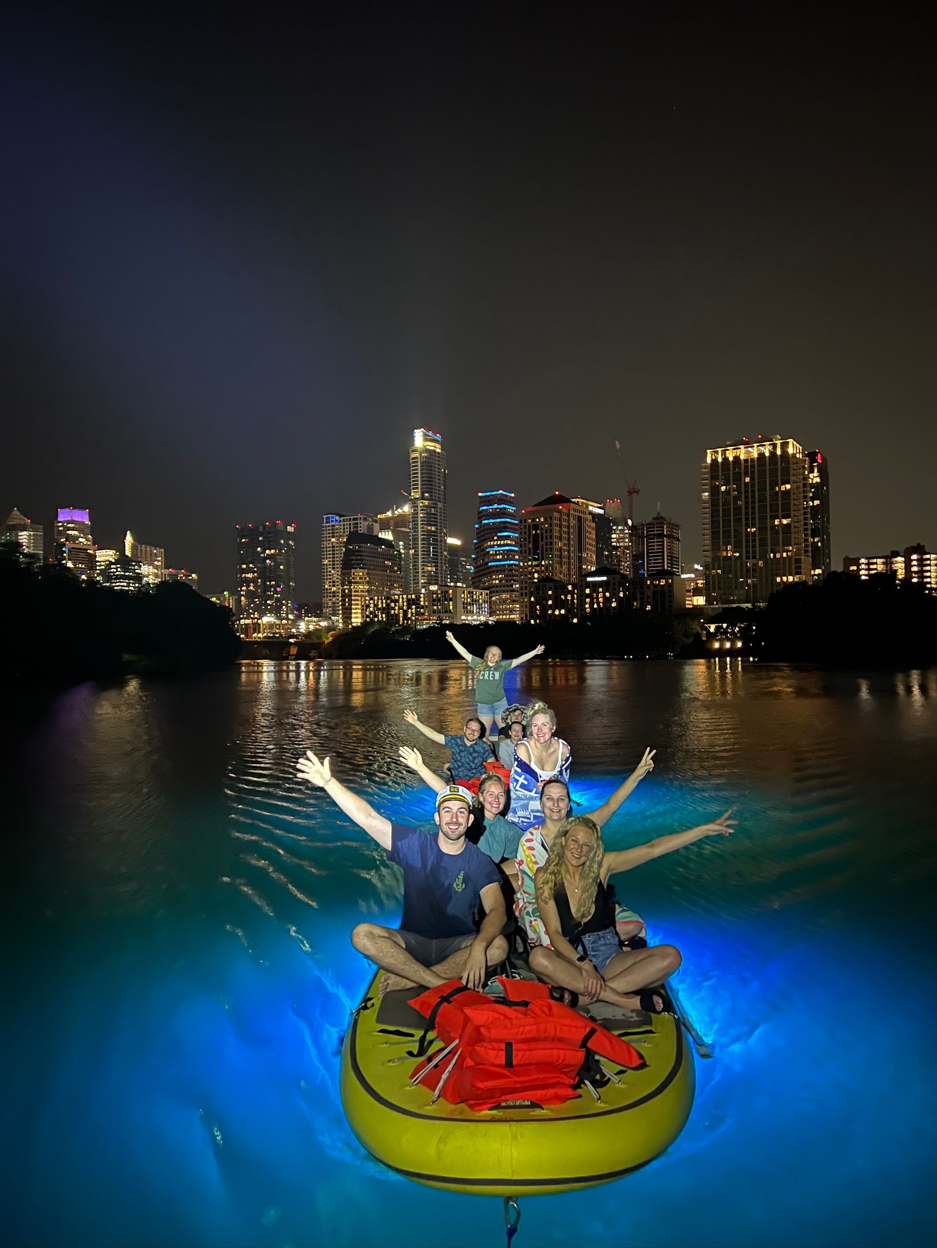 A group of people are sitting on a raft in the water at night.