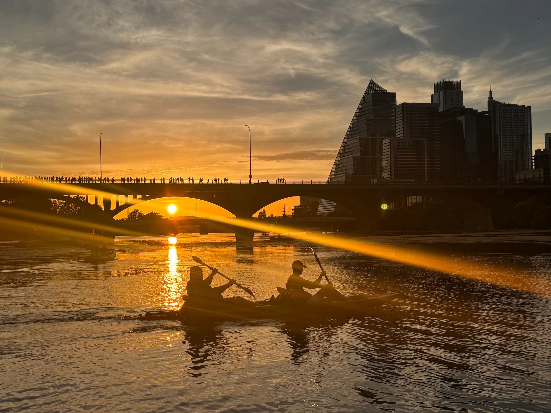 Sunset over Lady Bird Lake reflecting on the water with kayakers