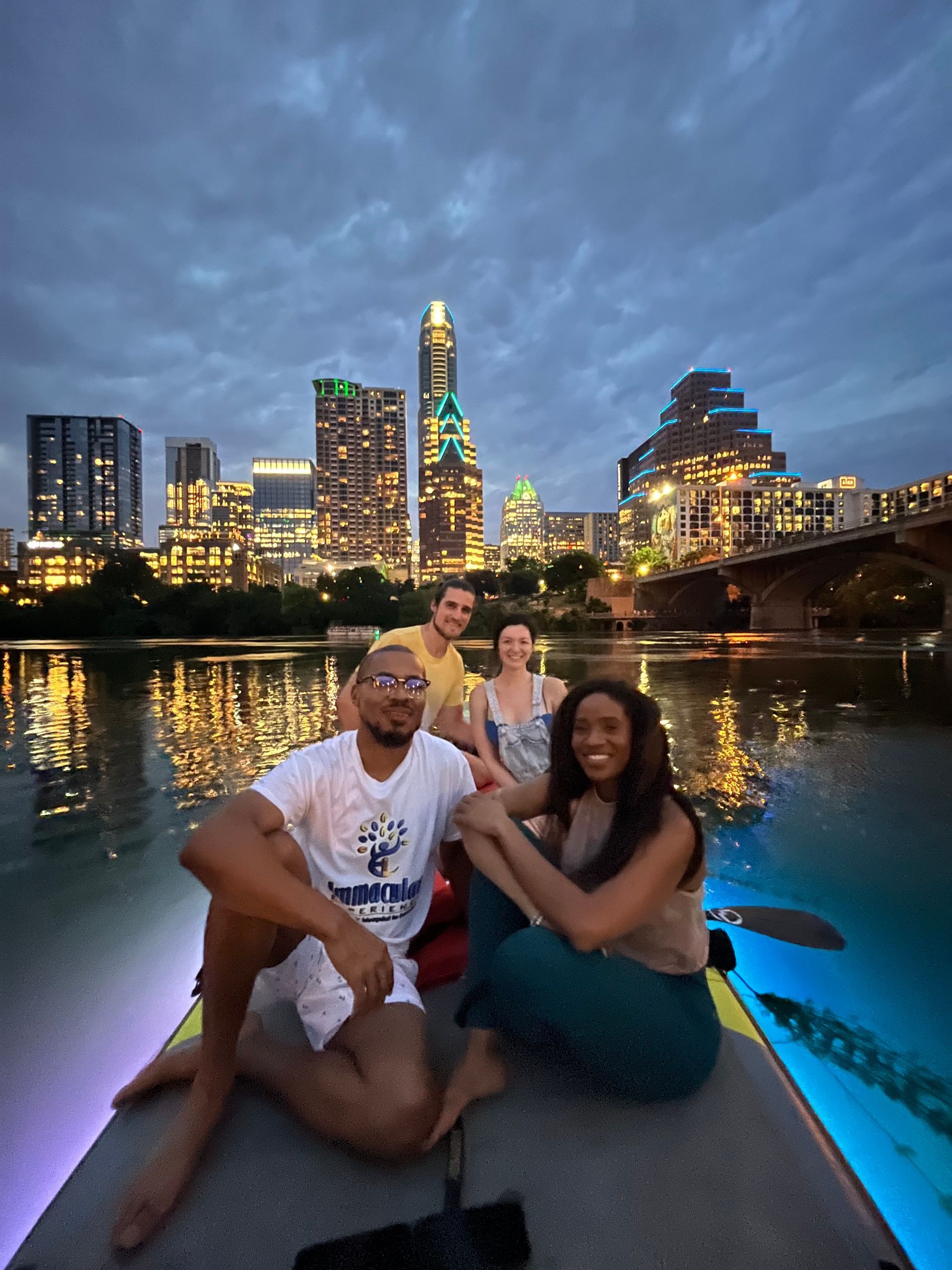 Paddleboarders on Lady Bird Lake using glowing paddleboards with the downtown lights behind them.
