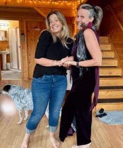 Two women are standing next to each other in a room with a dog.