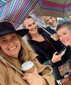 A group of women are posing for a picture under umbrellas.