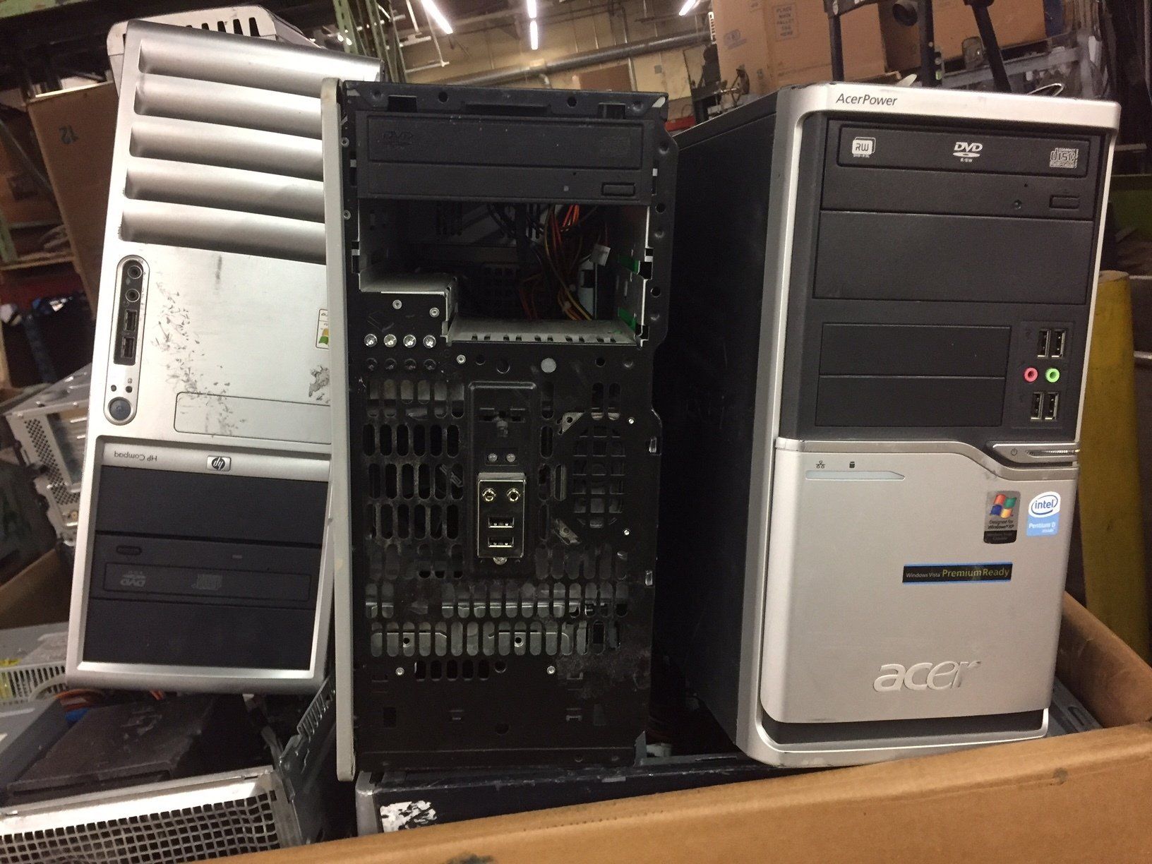 Three computer towers, one open and disassembled, on a workbench or table.