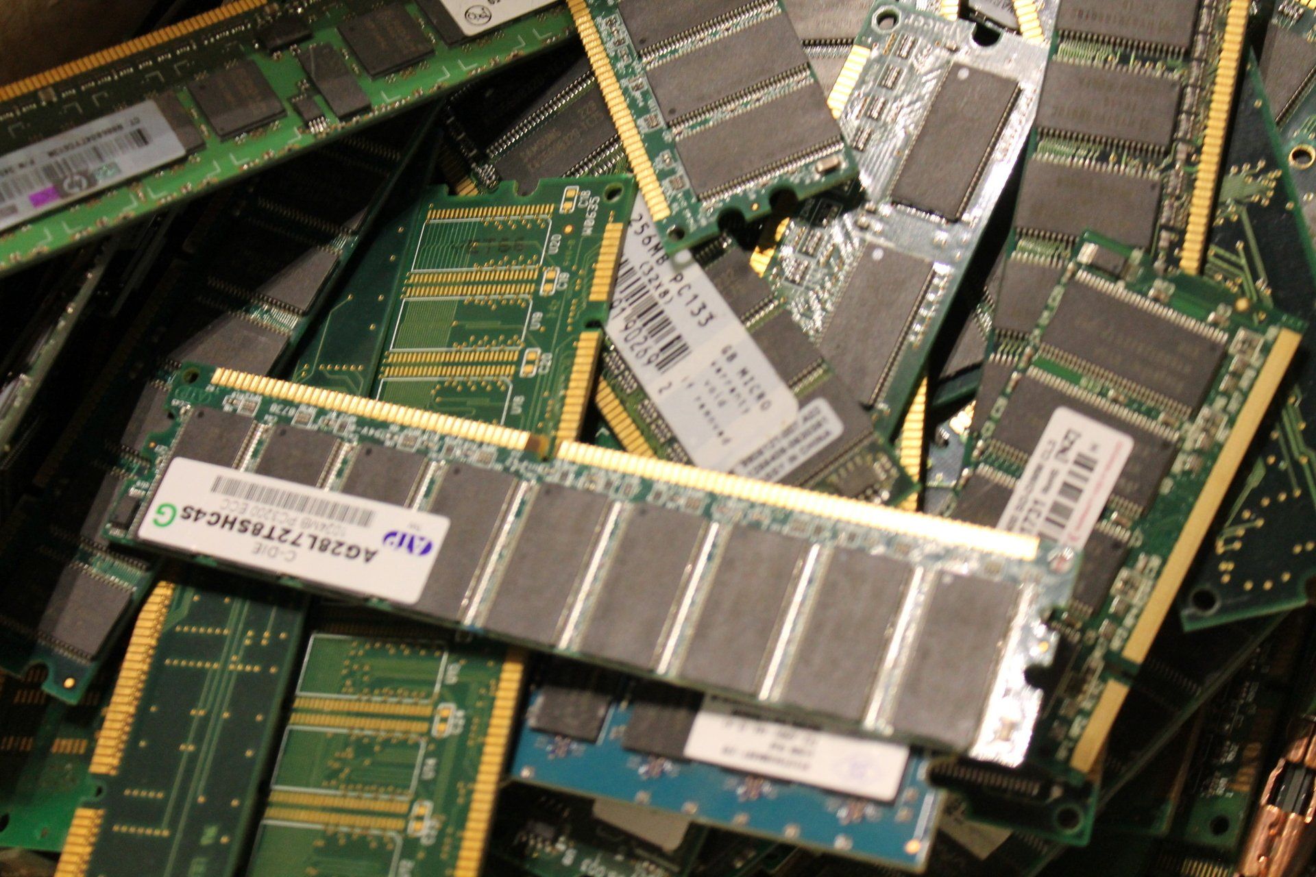 Pile of green computer RAM modules with silver heat spreaders.