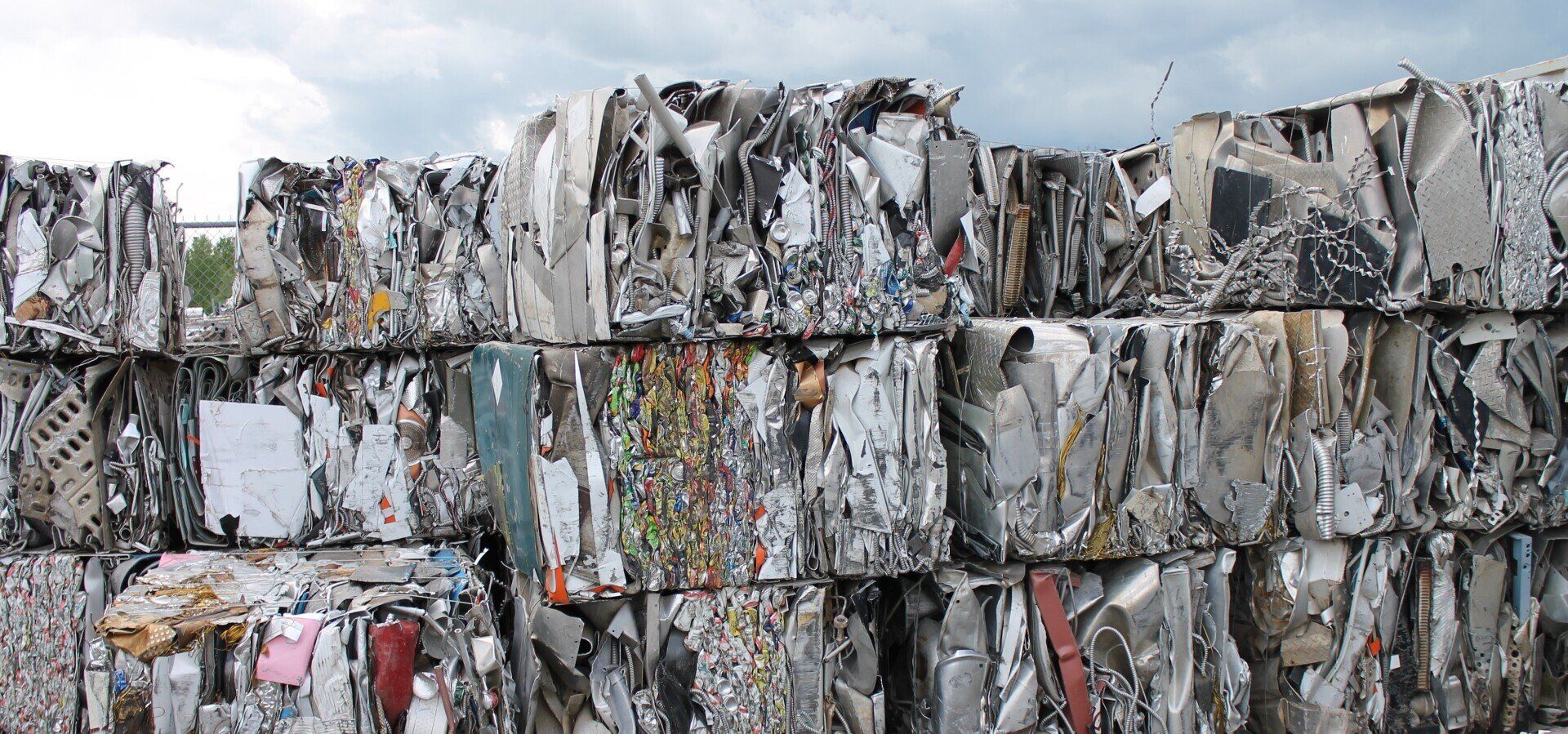 Stacked bundles of compressed, wrapped paper or cardboard for recycling, in gray and muted colors