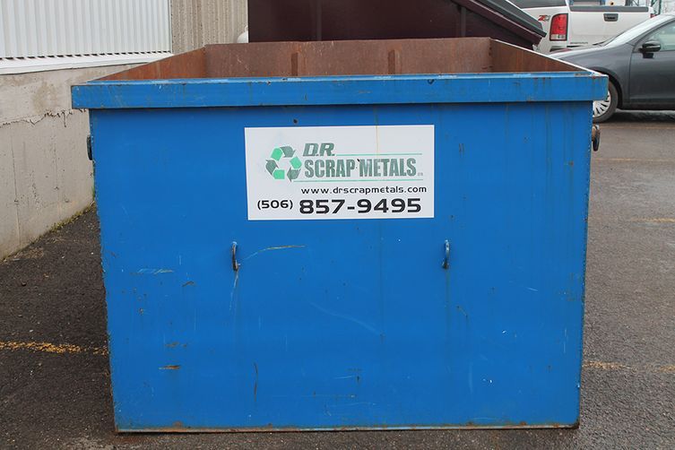 Blue metal dumpster with a sign on the front in an outdoor parking lot.