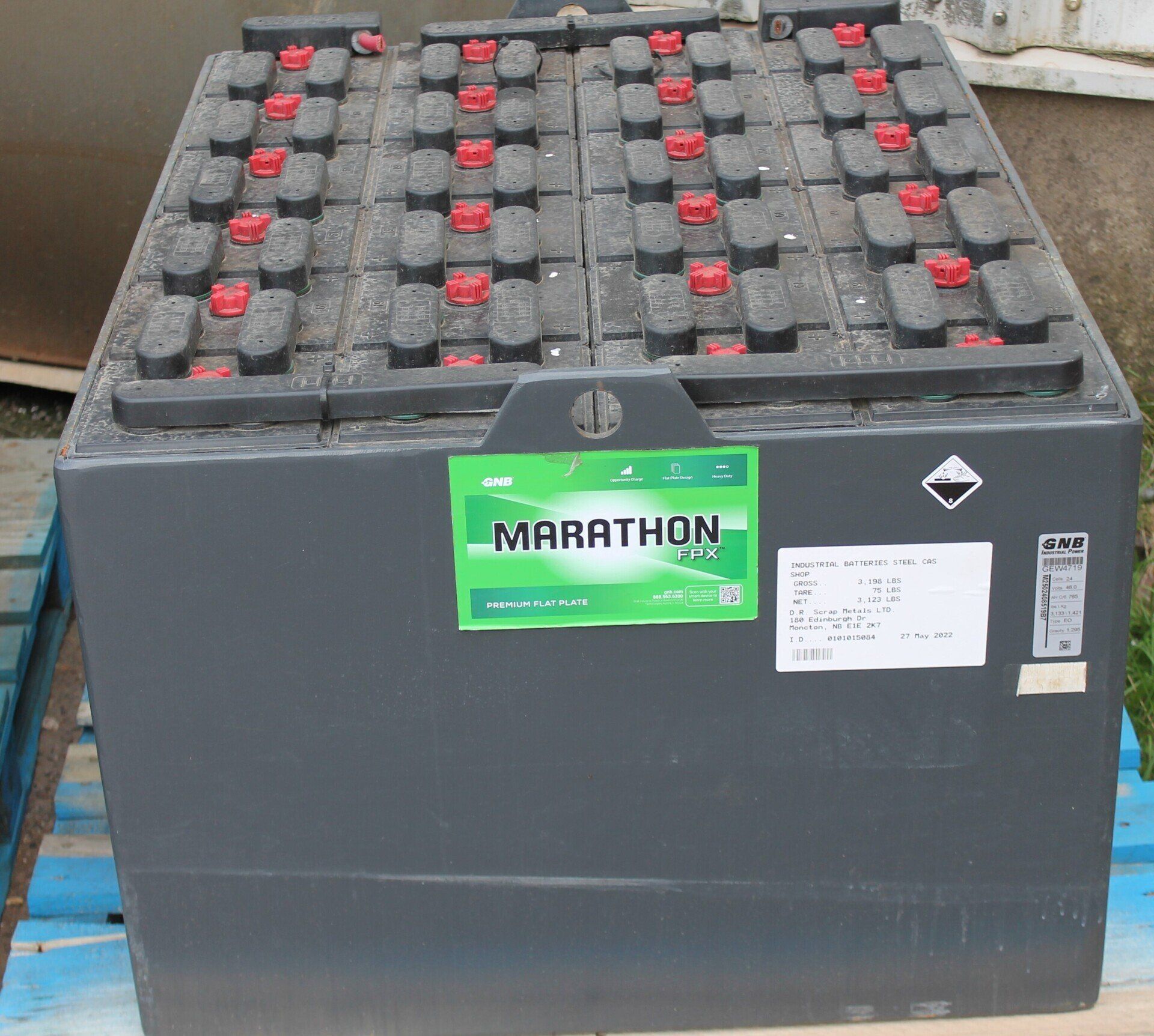 Large gray Marathon battery with red caps and labels, shown on a floor or pallet.