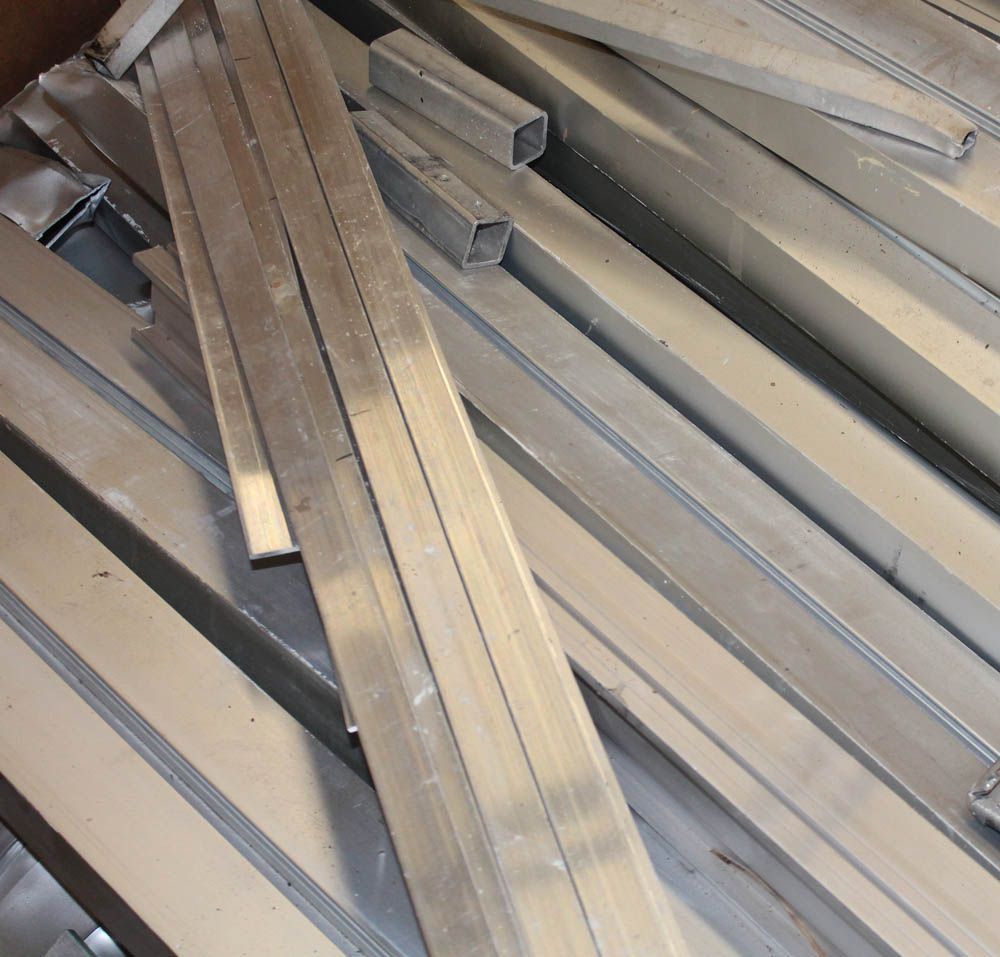 Pile of long silver metal bars stacked at angles in a storage area