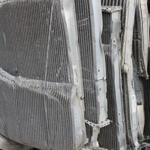 Stacked white mesh panels and curved metal frames in a close-up industrial scene