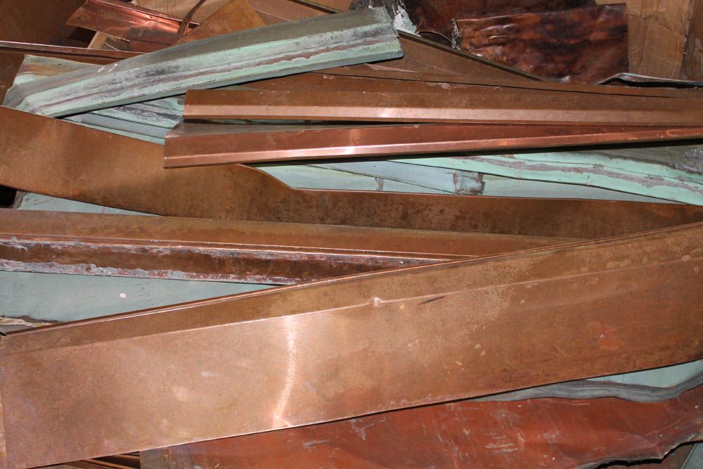 Pile of copper-colored metal strips stacked together on a work surface