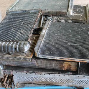 Stacked dirty metal radiator or heat exchanger panels in an industrial setting.