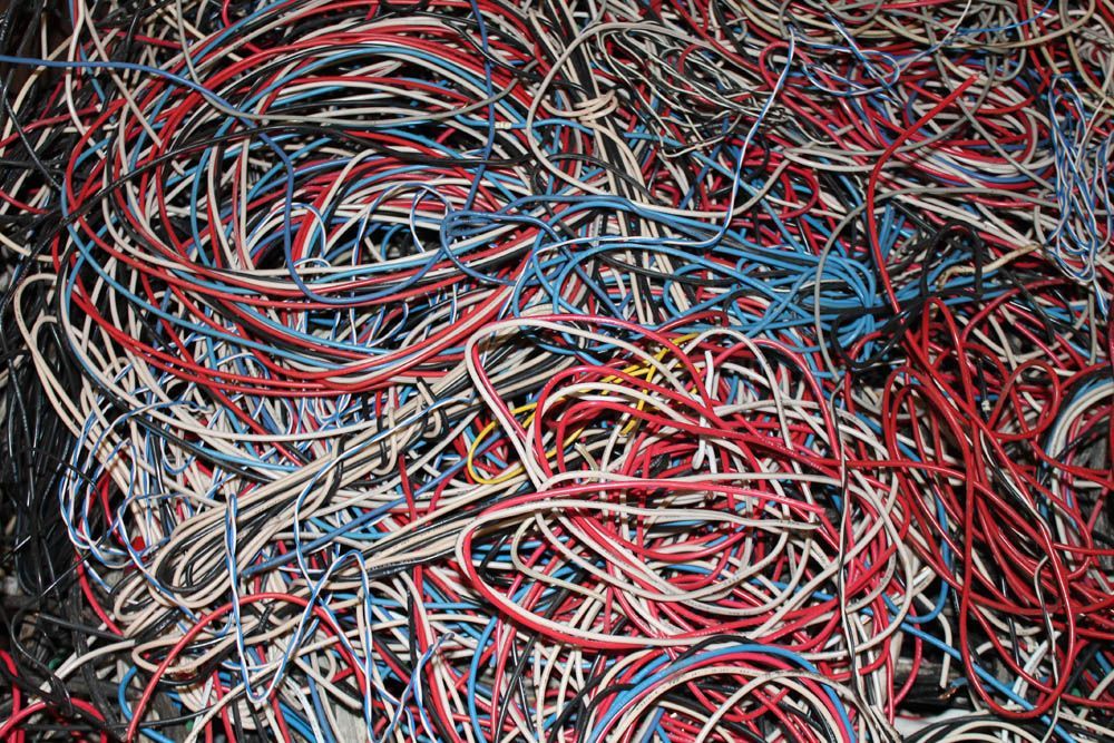 Tangled pile of red, blue, black, and white electrical wires and cables