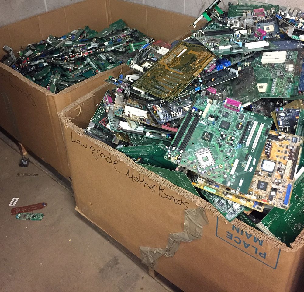 Cardboard boxes overflowing with discarded computer circuit boards and electronic scrap.