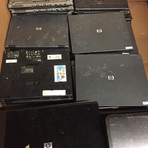 Stacked black HP laptop lids and one open laptop on a table, viewed from above
