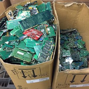 Cardboard boxes filled with assorted green and red circuit boards and electronic scrap
