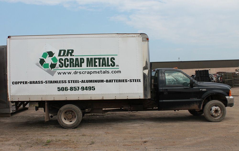 Black pickup truck with DR Scrap Metals logo and trailer parked on a dirt lot
