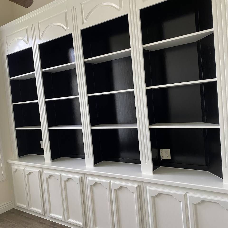 A room with white cabinets and black shelves.