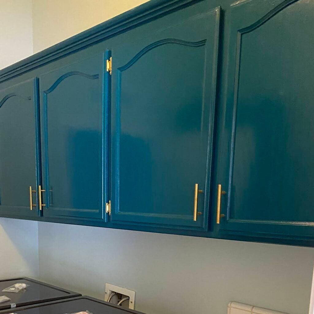 A laundry room with blue cabinets and a washer and dryer.