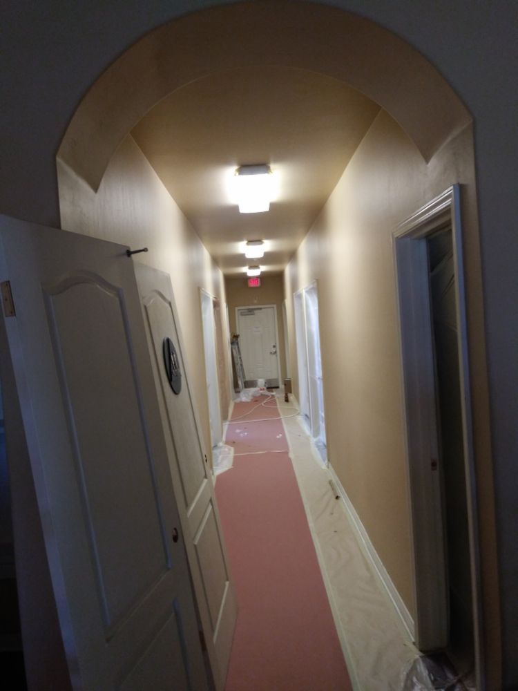 A long hallway with a pink carpet and white doors
