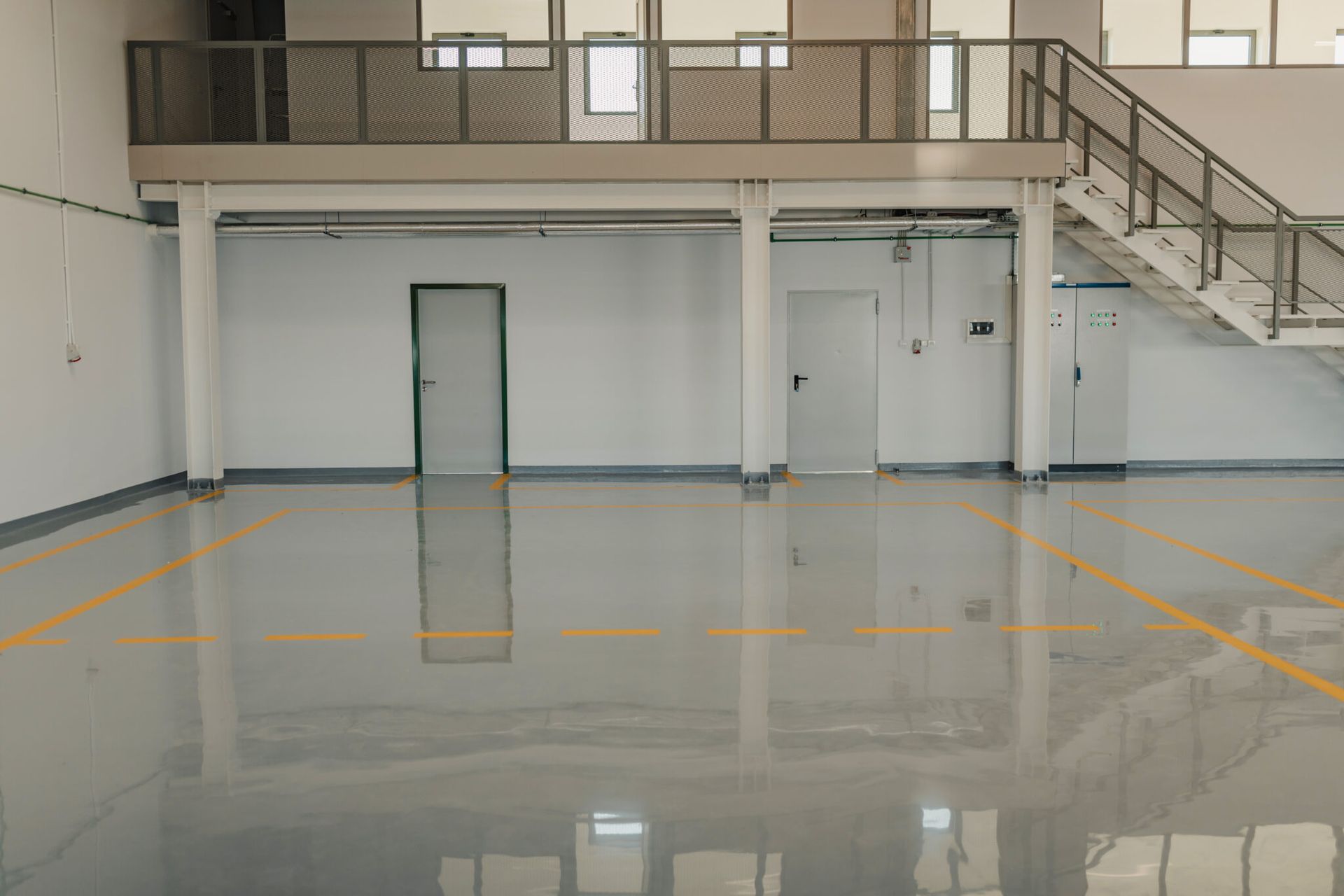 A large empty warehouse with a staircase and a balcony.