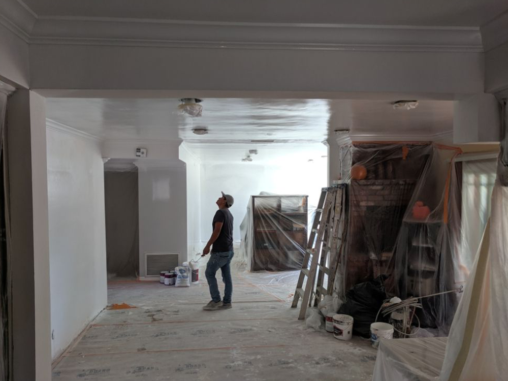 A man is standing in a room that is being painted.
