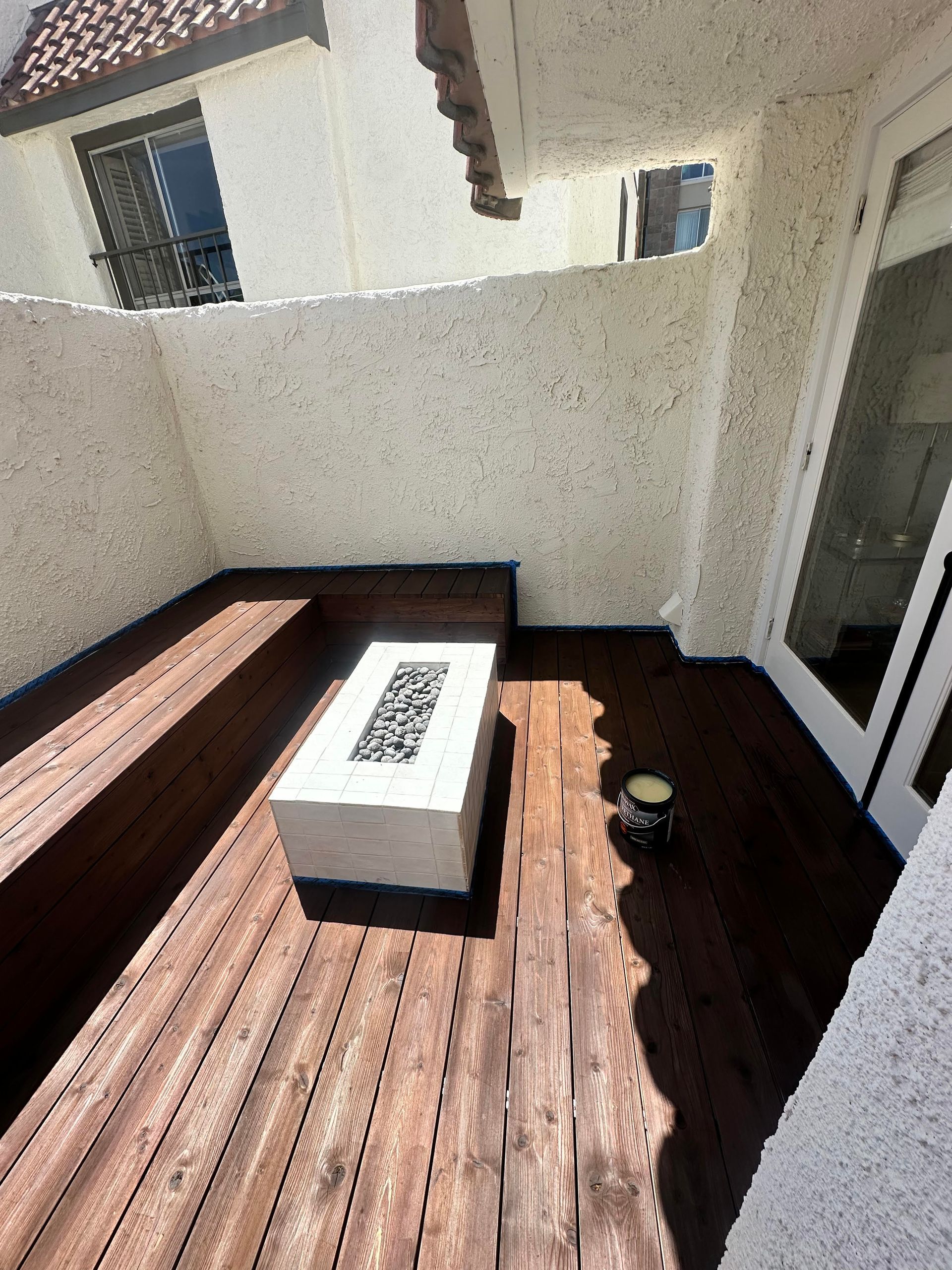 A wooden deck with a fire pit in the middle of it