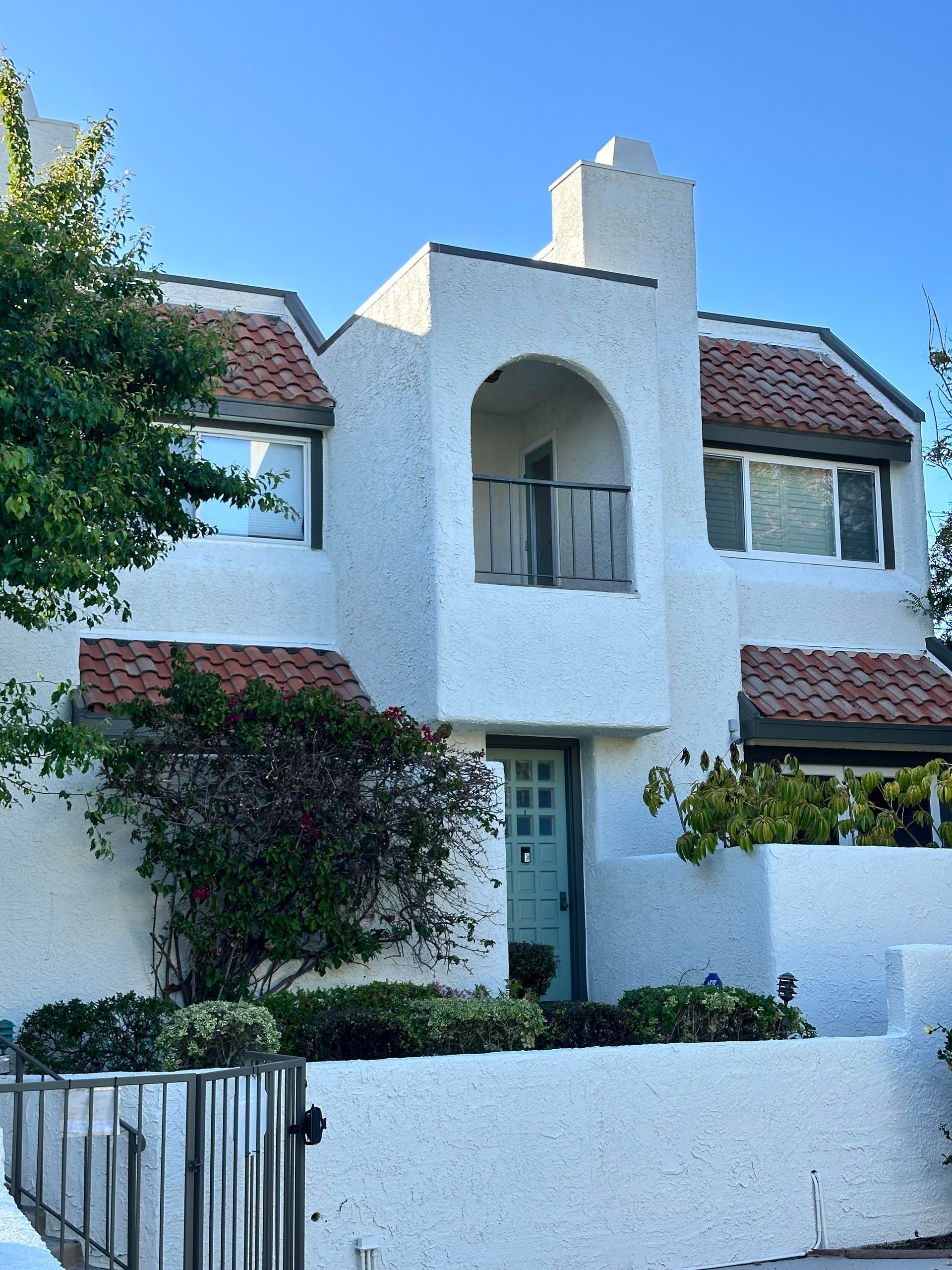 A white house with a blue door and a balcony