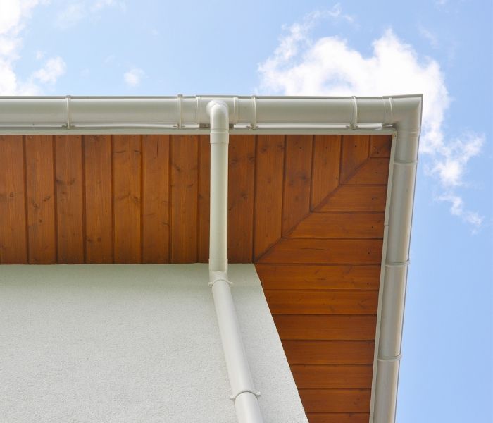 A man is standing on a scaffolding painting the side of a house.