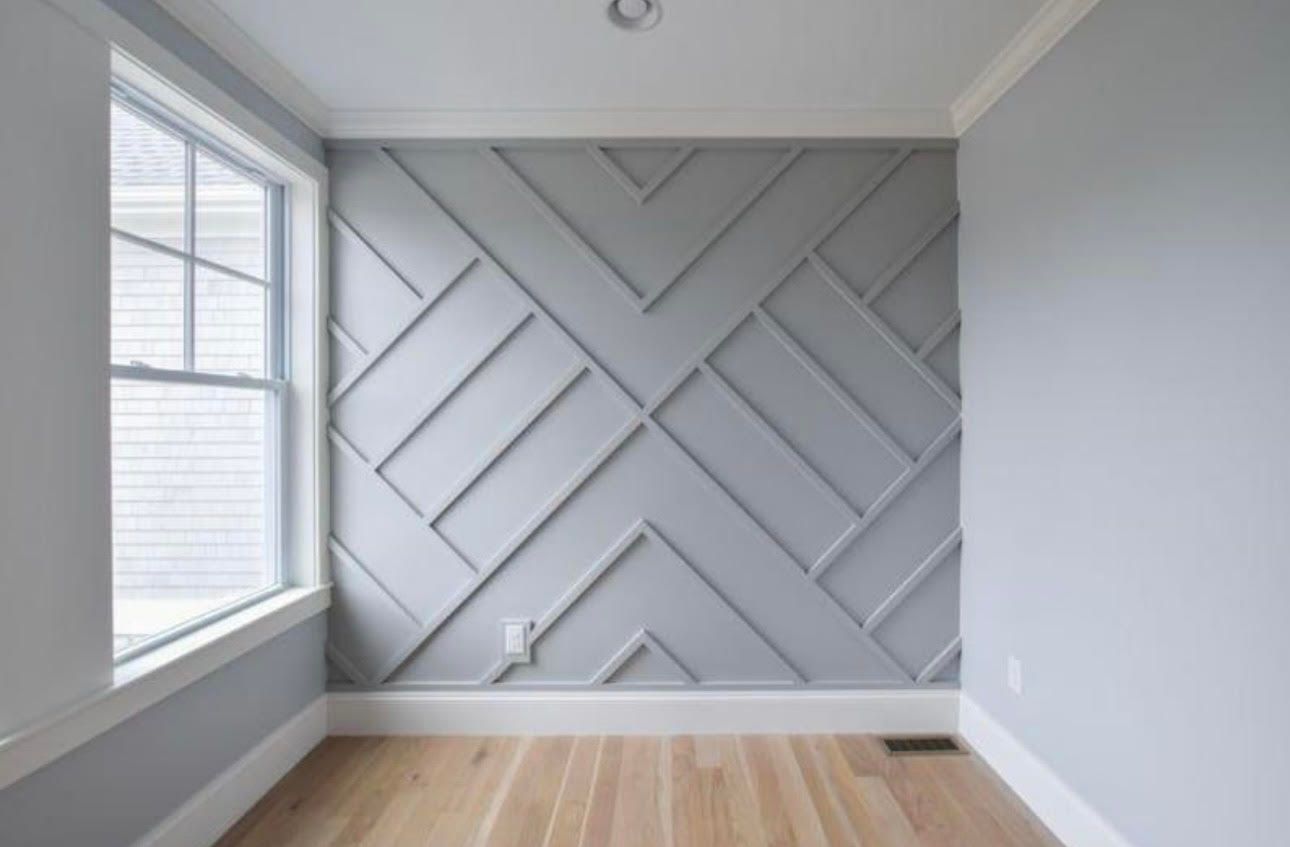 A room with a geometric pattern on the wall and a window.