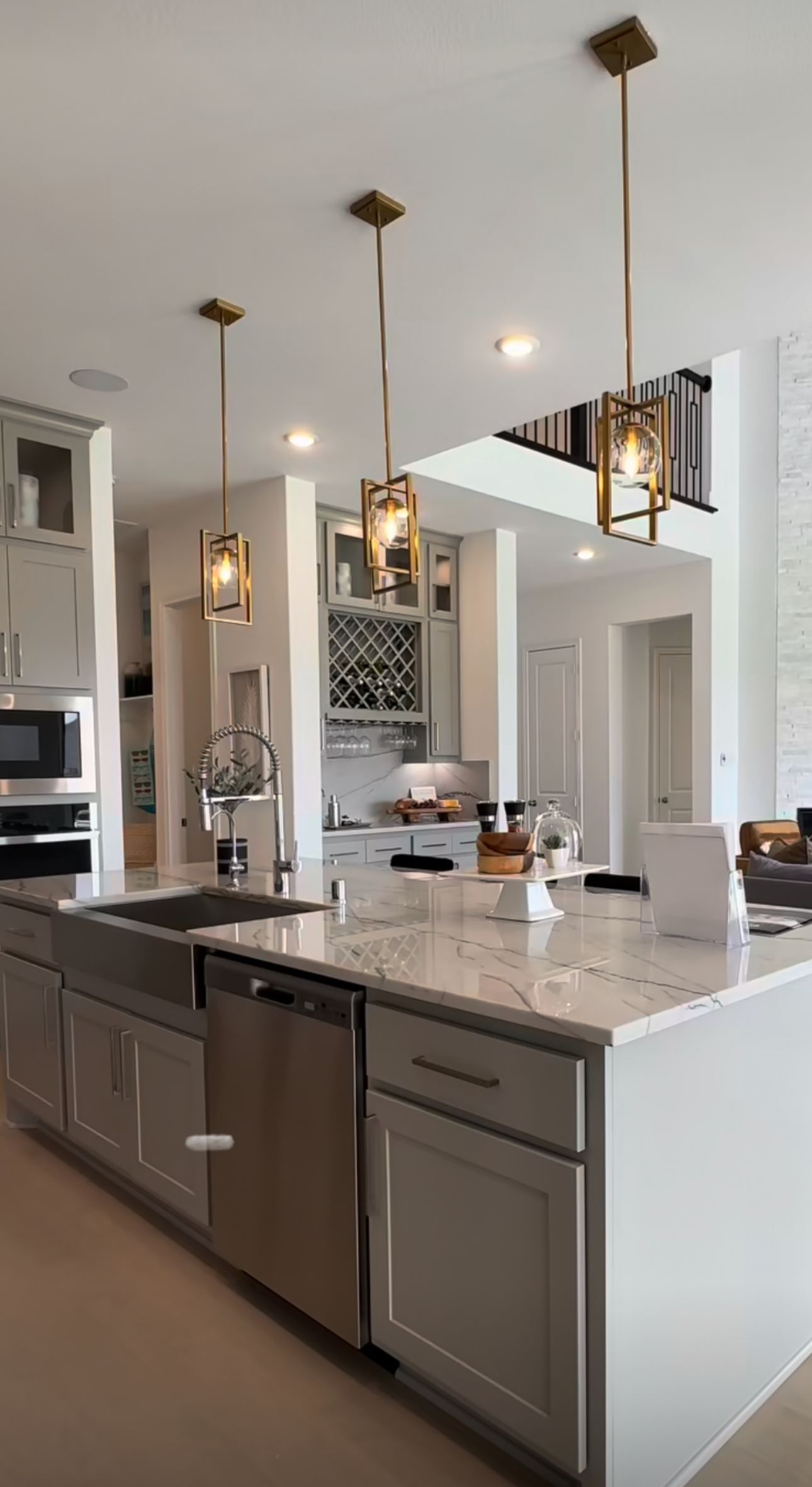 A kitchen with white cabinets , stainless steel appliances , a sink , and a large island.