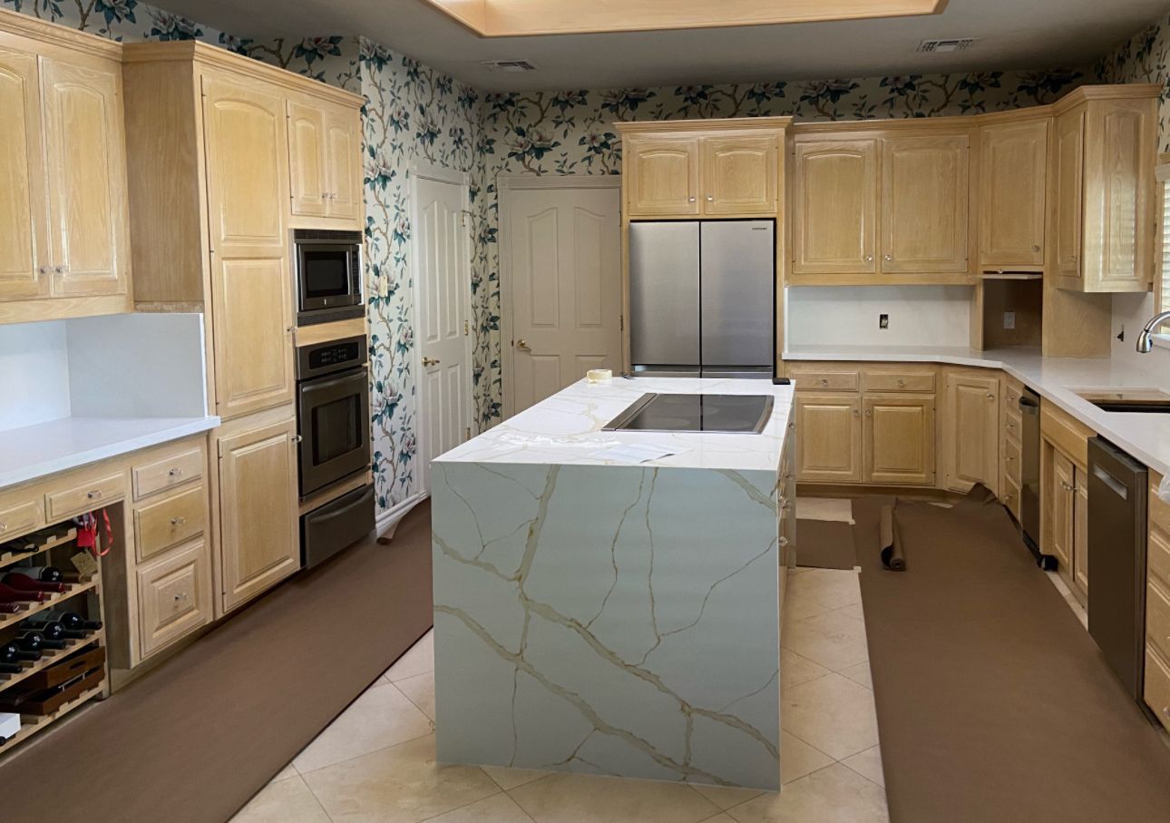 A kitchen with wooden cabinets and stainless steel appliances and a large island in the middle.