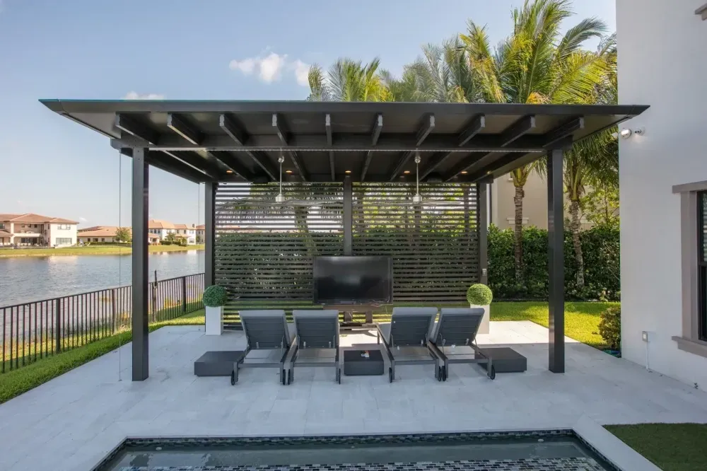 Modern patio with black pergola, lounge chairs, and pool beside a waterfront home