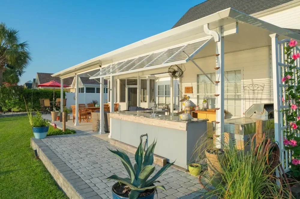 Modern house with a covered patio, potted plants, and a stone walkway in a sunny garden