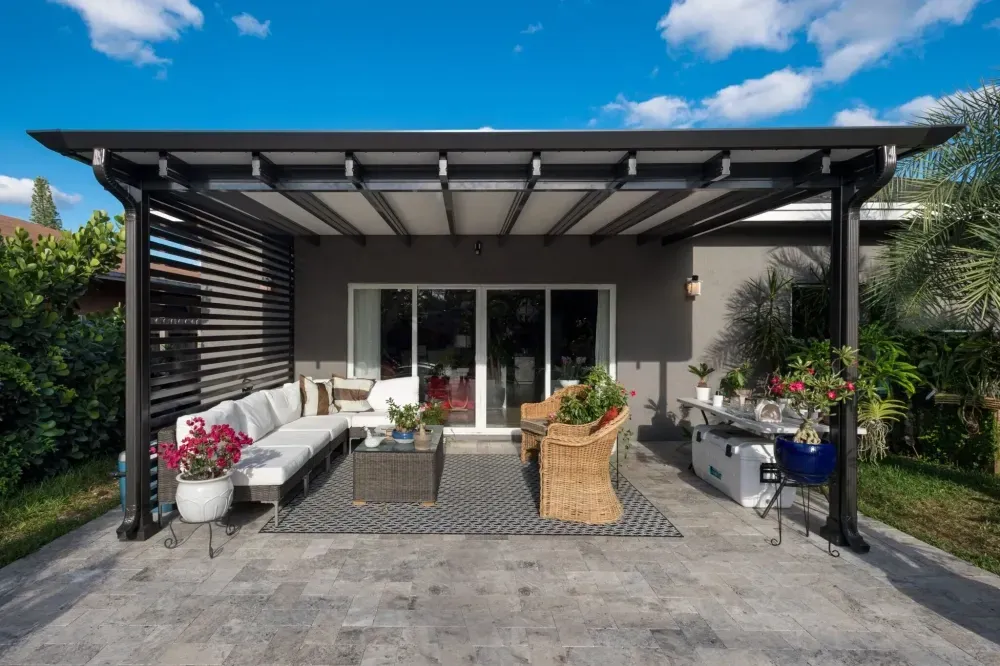 Modern patio with pergola, sliding doors, outdoor seating, and potted plants in front of a house