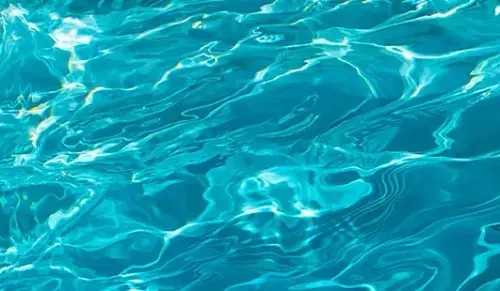 Turquoise pool water with bright sunlight reflections and gentle ripples