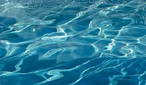 Blue rippling water with bright sunlight reflections on the surface