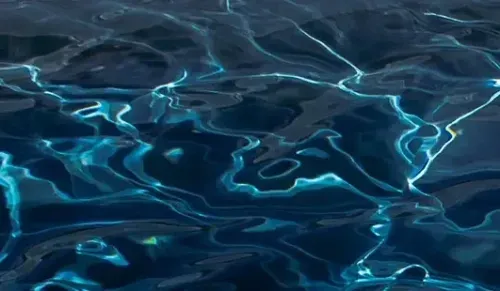 Blue water surface with shimmering light reflections and ripples