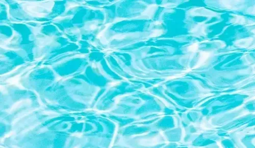 Light turquoise water surface with sunlight reflections and gentle ripples