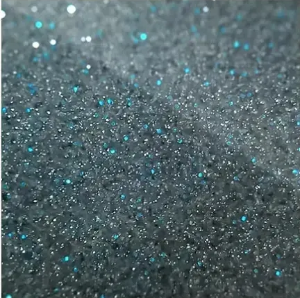 Close-up of dark gray glitter with scattered blue sparkles