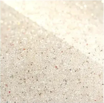 Close-up of pale beige sand with tiny specks and a softly blurred background