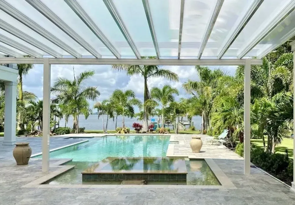 Modern tropical patio with infinity pool, palms, and ocean view under a white pergola