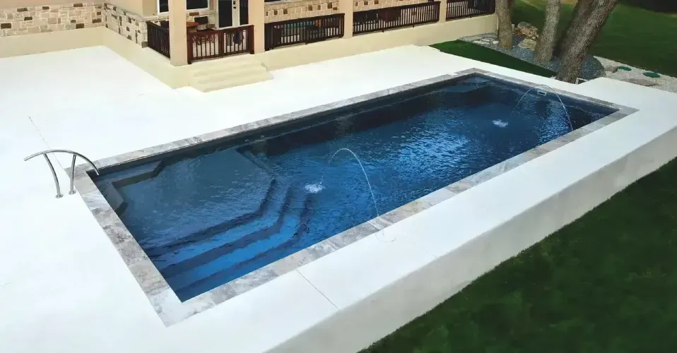 Modern luxury house with a lit pool, deck chairs, and large glass windows at dusk