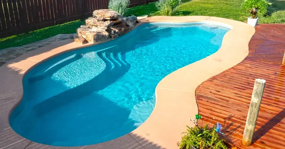 Modern two-story house with a pool and spacious white patio under a clear blue sky