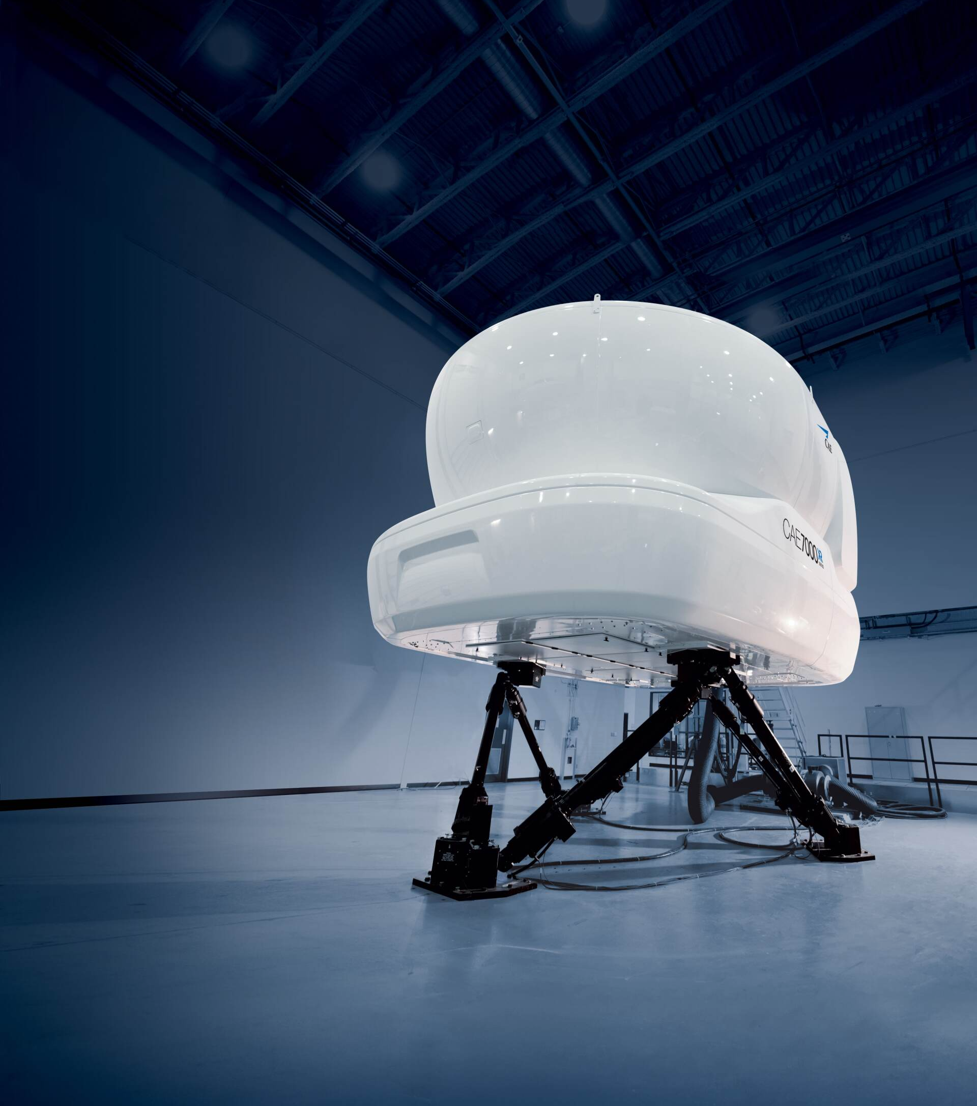White radar dome on black support legs in a snowy hangar, lit by cool blue light.