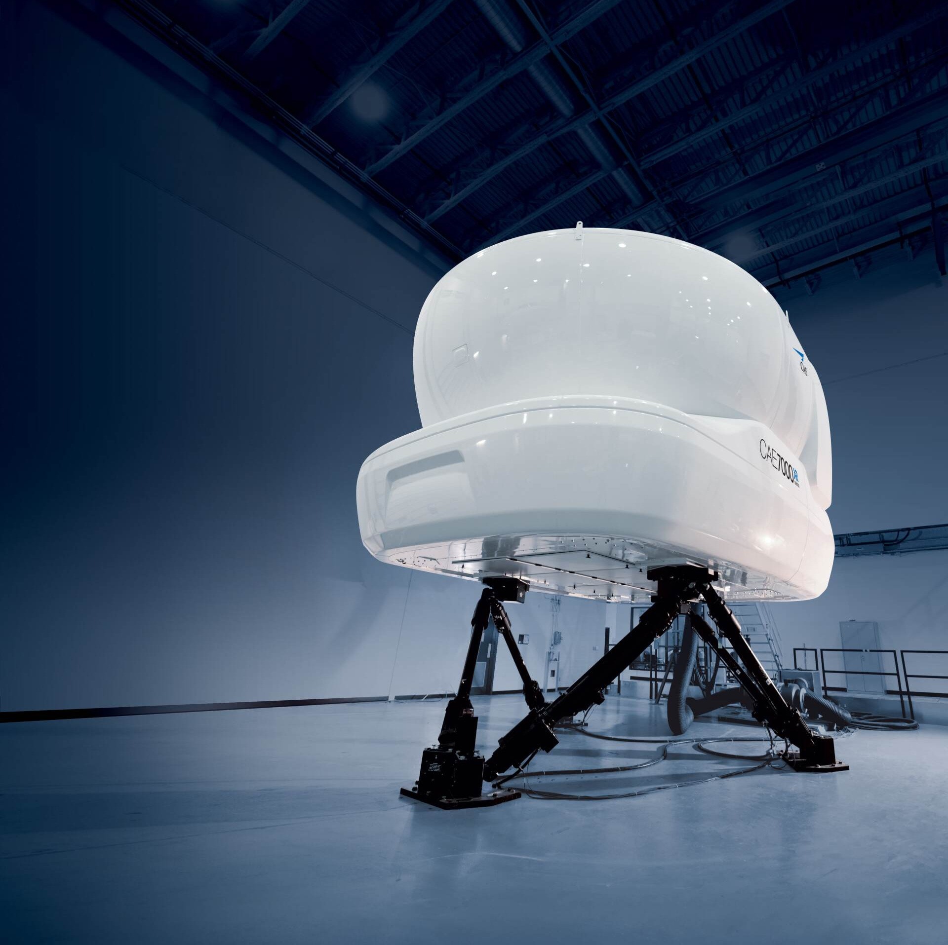 White telescope dome on black supports in a dim blue observatory interior
