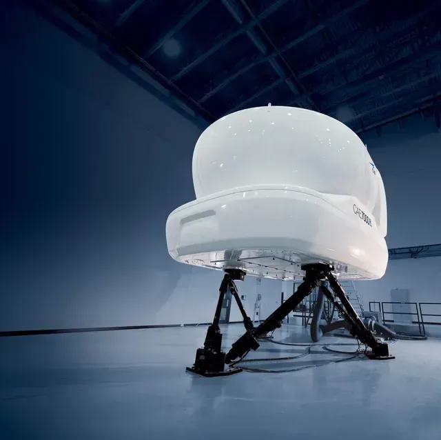 White telescope dome on black supports in a dim blue observatory interior